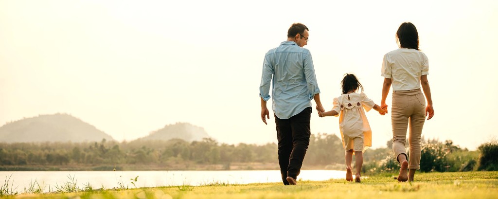 A family walking together beside a lake at golden hour